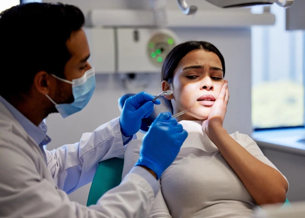 A dentist examining a patient experiencing pain from a broken or chipped tooth