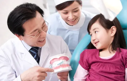 A dentist showing how to use tooth brush to a child