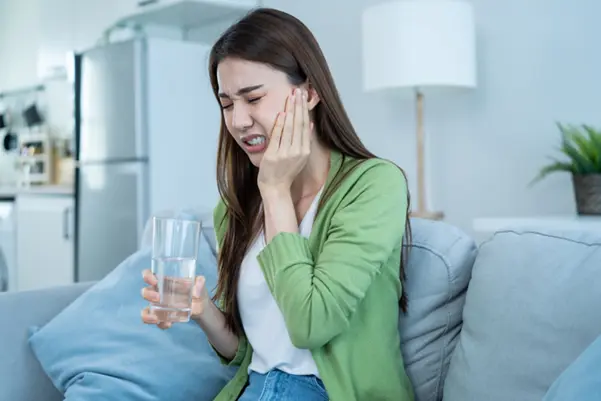 A woman rinsing her mouth with water as a first-aid step for a toothache