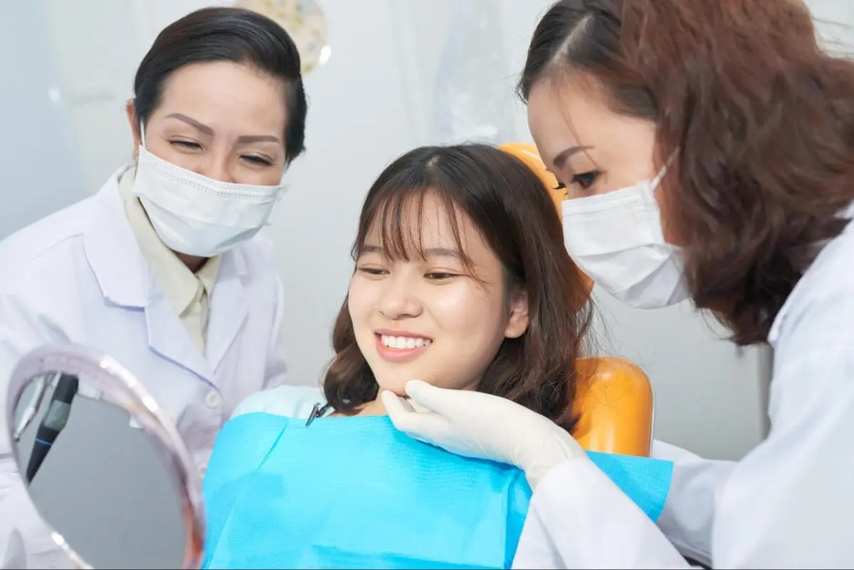 A happy patient observing her healthy smile after receiving periodontal care at Ginza Dental in Clementi.