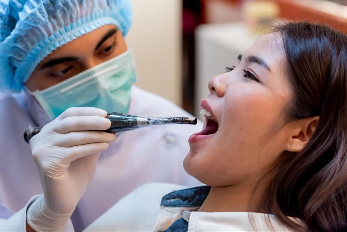 Professional dentist at Ginza Dental clinic examining a patient’s mouth.