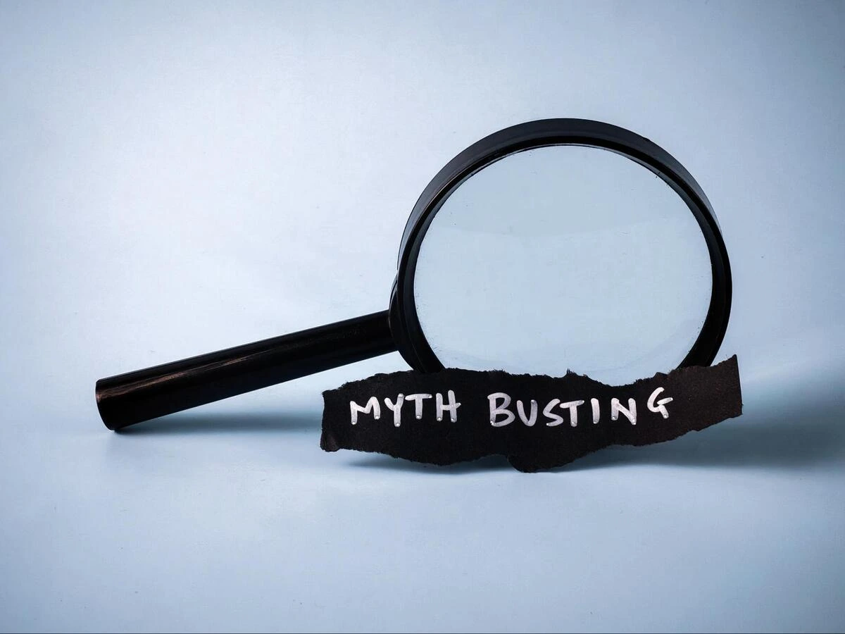 Magnifying glass examining a piece of paper with the words Myth Busting, representing common misconceptions about root canal treatment
